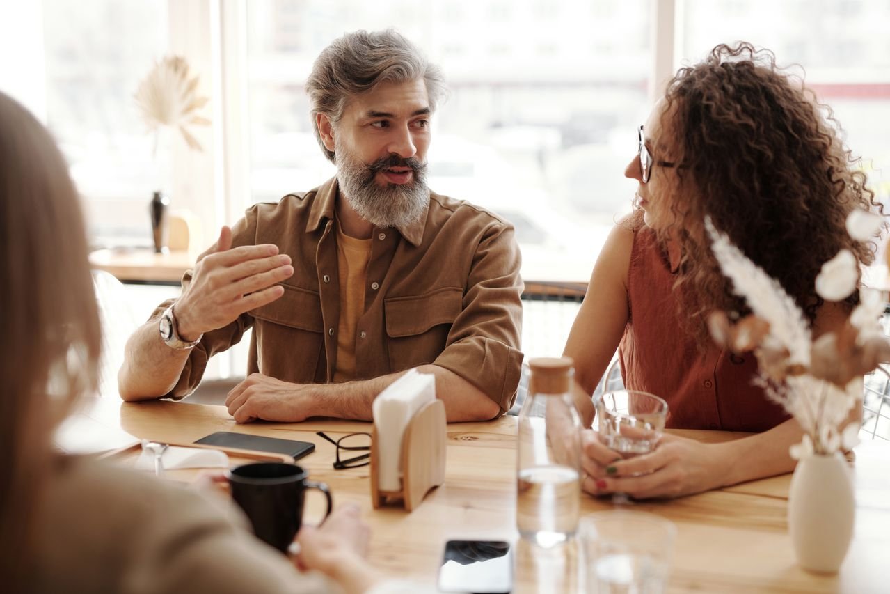 A friendly discussion among colleagues in a cozy cafe environment about understanding people and ourselves.